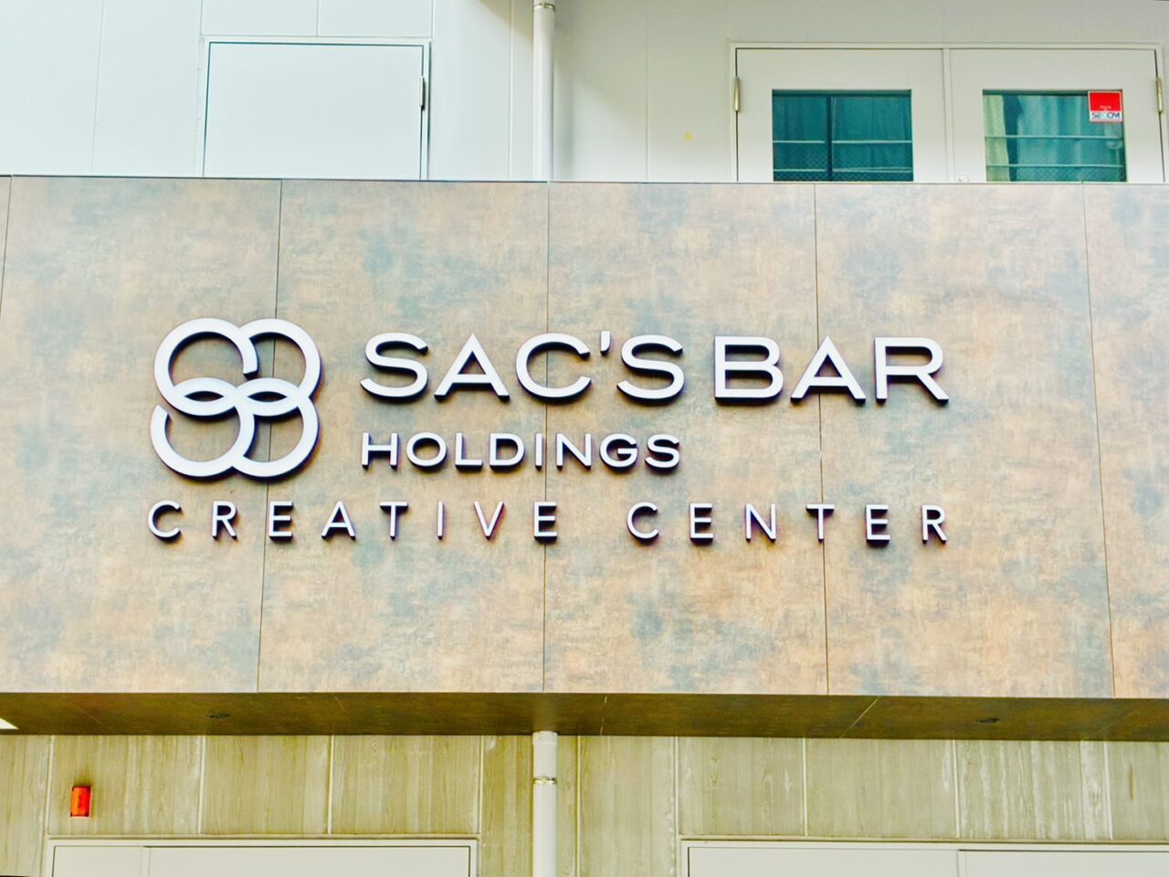 ビルに掲げられた「SAC'S BAR HOLDINGS」の表示